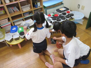 カブトムシに製作したカブトムシを見せている子どもたちの写真