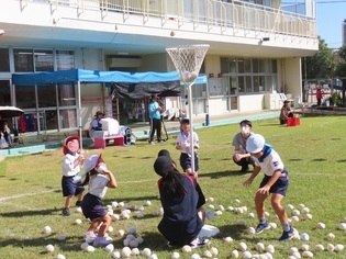 中学生と玉入れをしている子どもたちの写真