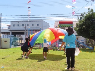 中学生とパラバルーンをしている子どもたちの写真